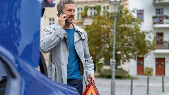 Man standing at BMW trunk
Man standing at BMW trunk with Smartphone and warning triangle