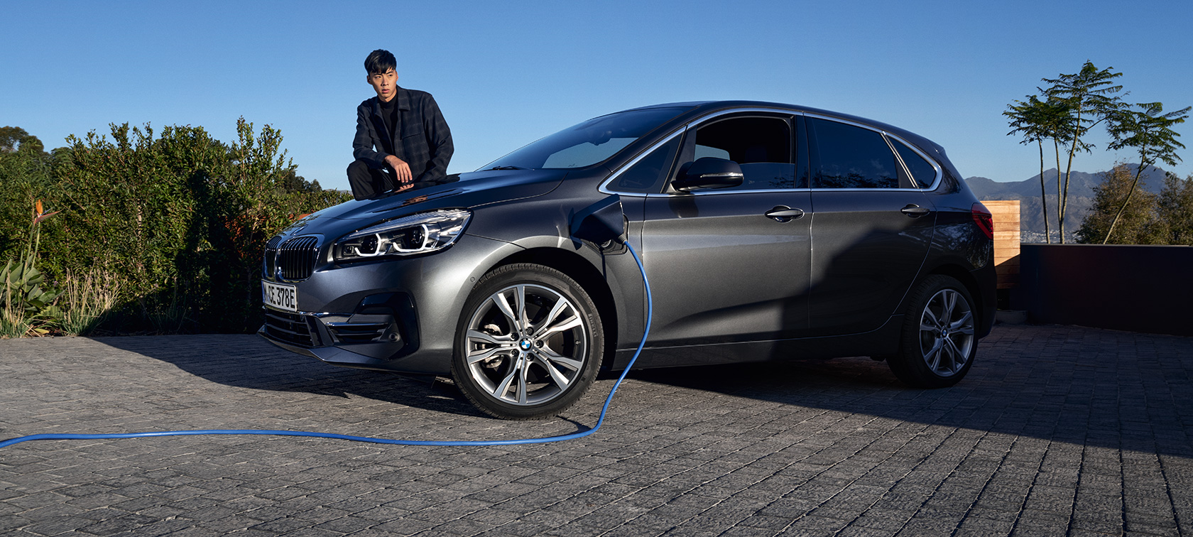 Plug-in hybrid BMW 225xe Active Tourer F45 three-quarter side view charging Plug-in hybrid BMW 225xe Active Tourer F45 three-quarter side view charging with model