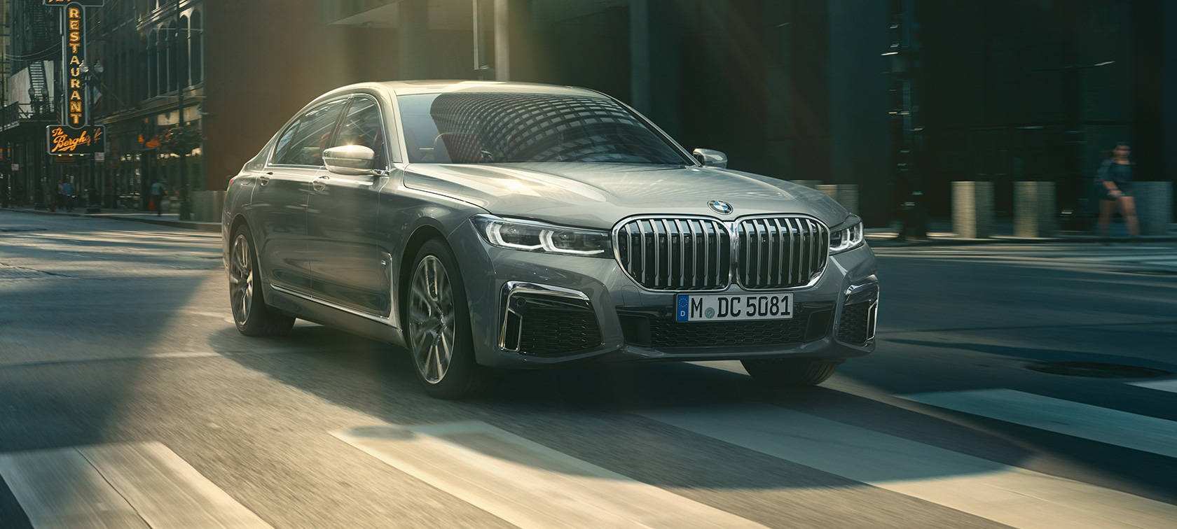 BMW 7 Series Sedan G11 G12 2019 Bernina Grey Amber Effect three-quarter front view driving BMW 7 Series Sedan G11 G12 2019 Bernina Grey Amber Effect three-quarter front view driving through urban setting