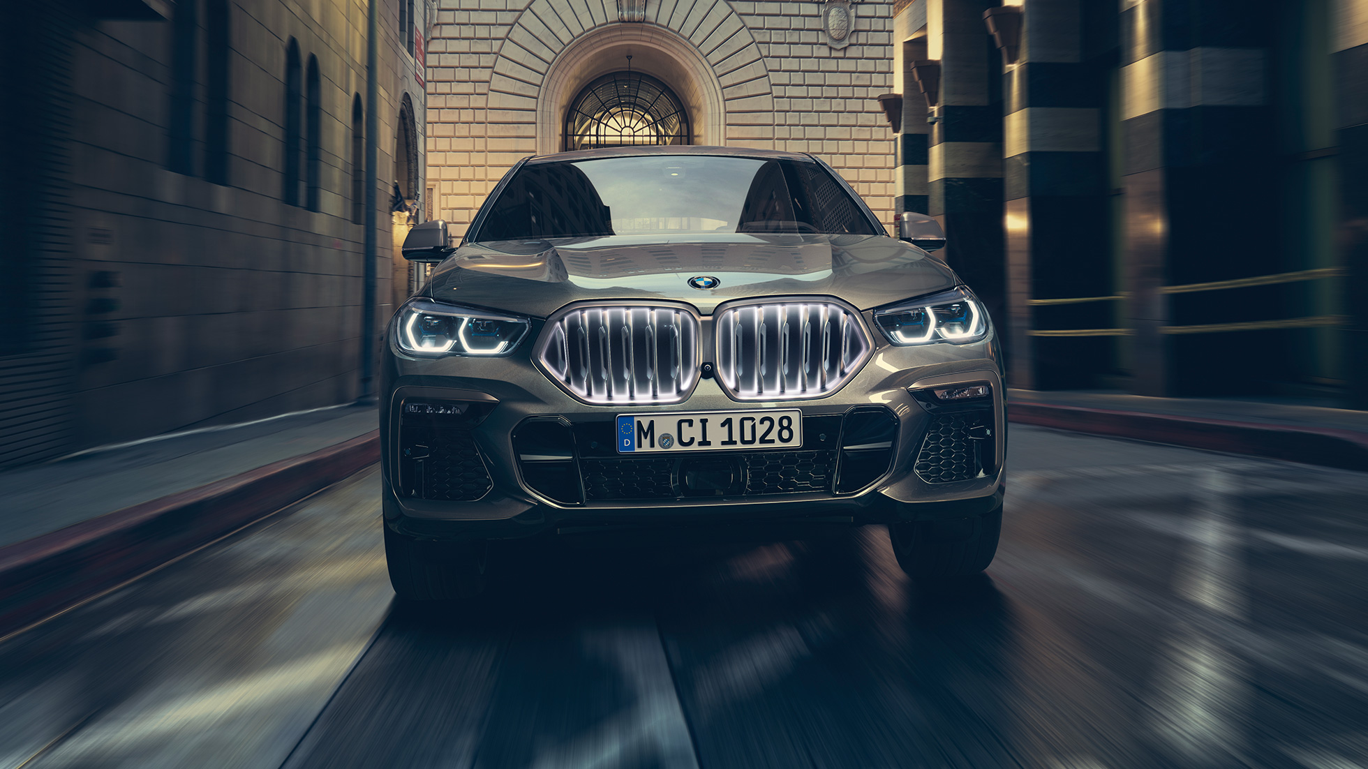 BMW X6 M50i with BMW kindey grille ‚Iconic Glow‘ . BMW X6 M50i in front perspective in front of an urban setting.