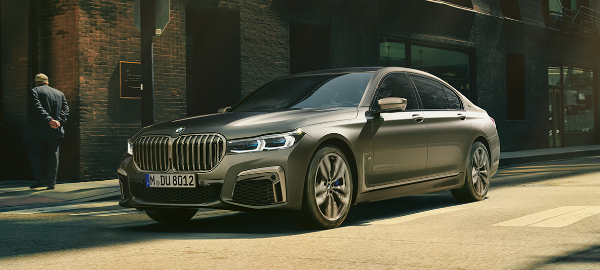 BMW M760Li xDrive Sedan G11 G12 2019 Frozen Dark Silver metallic three-quarter rear view driving in urban setting BMW M760Li xDrive Sedan G11 G12 2019 Frozen Dark Silver metallic three-quarter rear view driving in urban setting