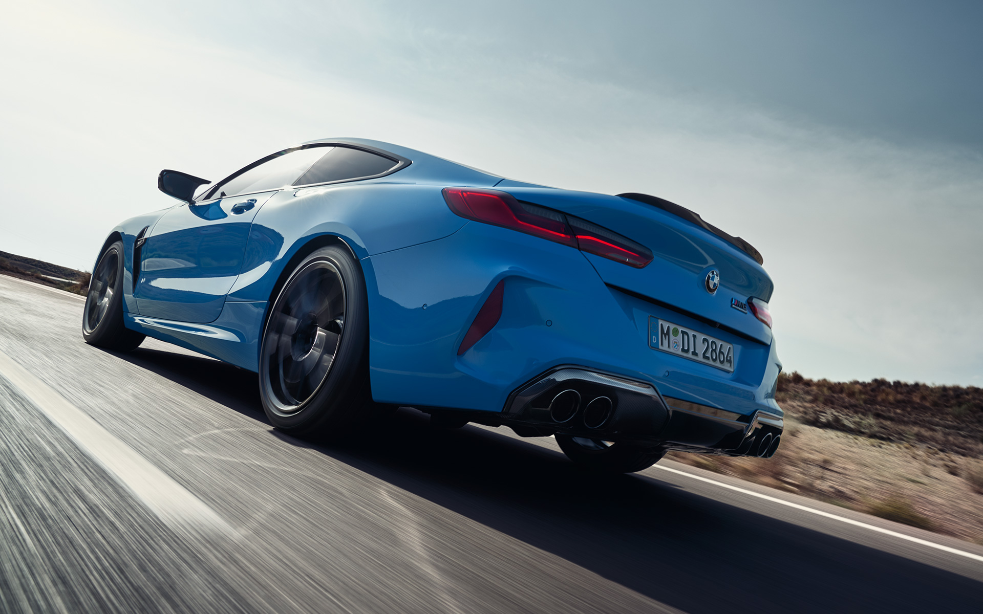 The BMW M8 Competition Coupé F92 LCI 2022 three-quarter rear view driving The BMW M8 Competition Coupé F92 LCI Facelift 2022 Daytona Beach blue uni three-quarter rear view driving on a highway