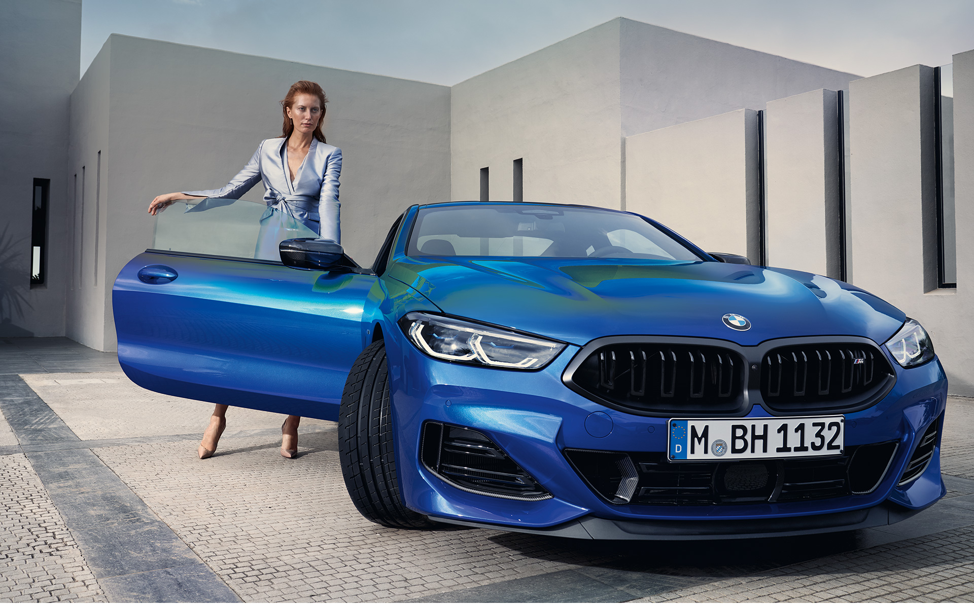 The BMW M850i xDrive Coupé G15 LCI Facelift 2022 front view standing The BMW M850i xDrive Coupé G15 LCI Facelift 2022 M Portimao Blue metallic front view standing with female model in open front door