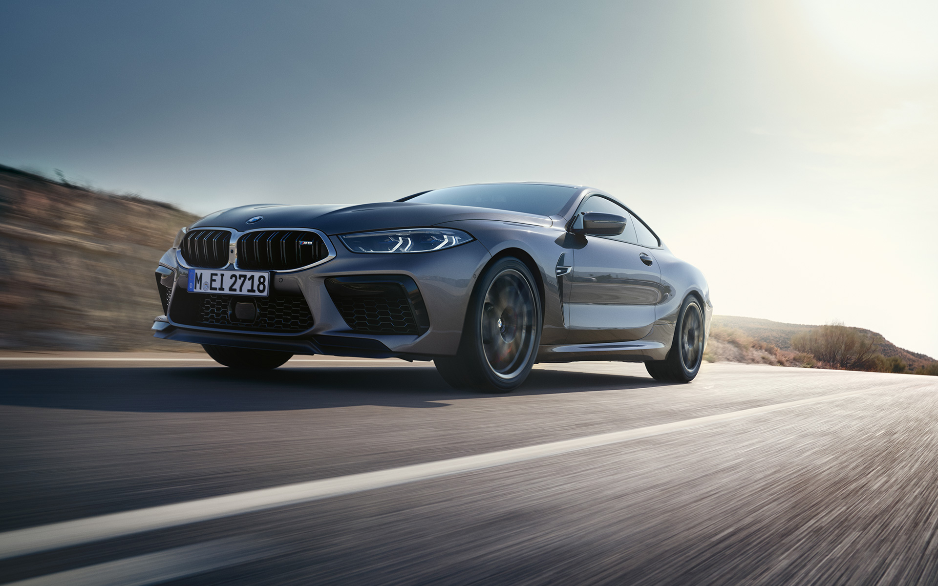 Three-quarter front view the BMW M8 Coupé F92 LCI Facelift 2022 driving on a highway The BMW M8 Coupé F92 LCI Facelift 2022 Skyscraper grey metallic three-quarter front view driving on a highway low angle shot