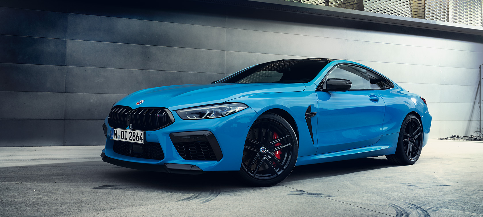The BMW M8 Competition Coupé F92 LCI Facelift 2022 Daytona Beach Blue uni three-quarter side view standing in front of a wall