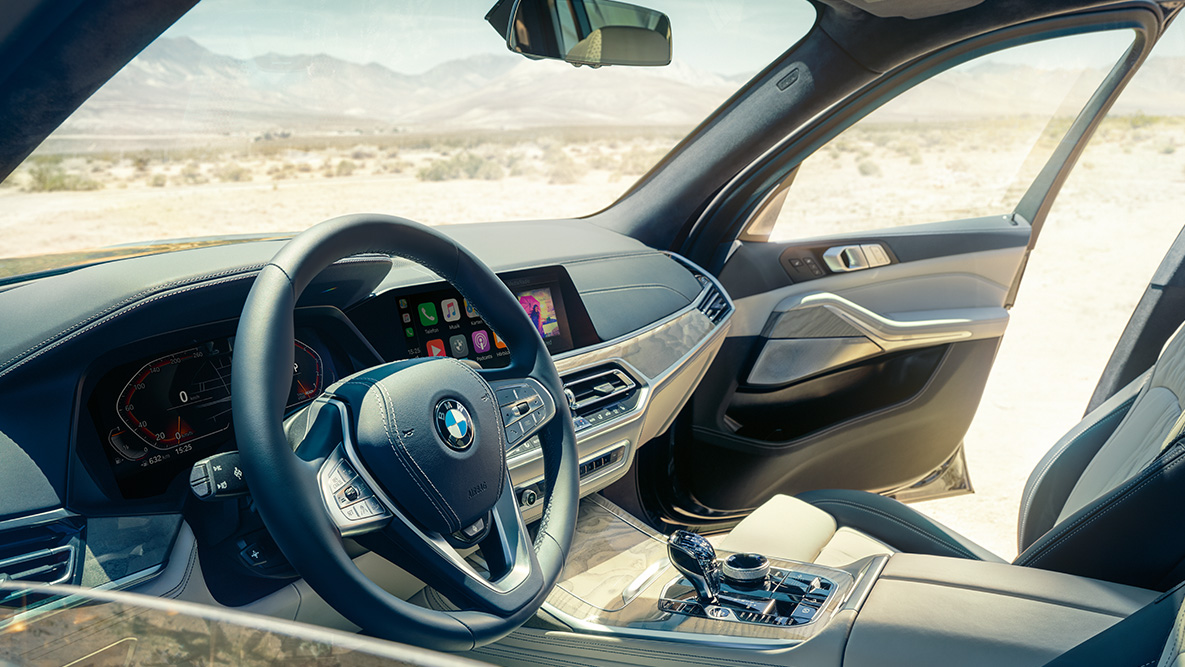 BMW X7 interior: view from the outside into the first row of seats with a view of the steering wheel, instrument cluster and leather seats BMW X7 interior