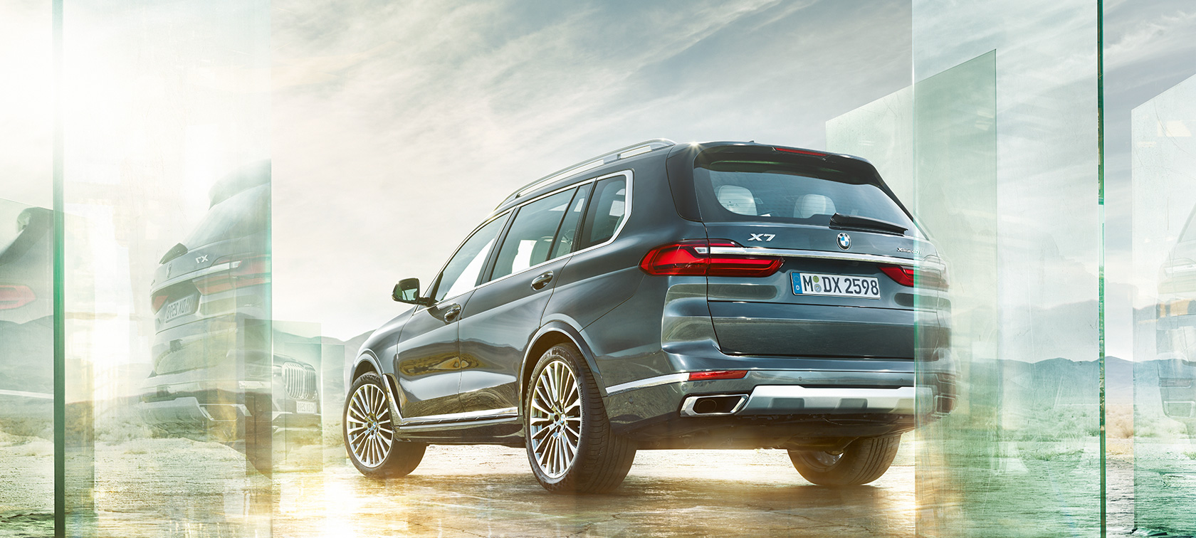 BMW X7 three-quarter rear view driving BMW X7 G07 2019 Arctic Grey three-quarter rear view driving