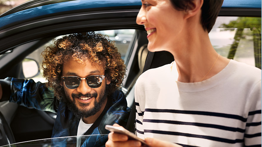 BMW Connected Man in BMW and woman outside the BMW using BMW Connected on smartphone