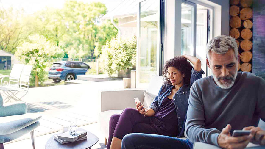 Remote Services Man and woman sitting on sofa and using Remote Services on their smartphones