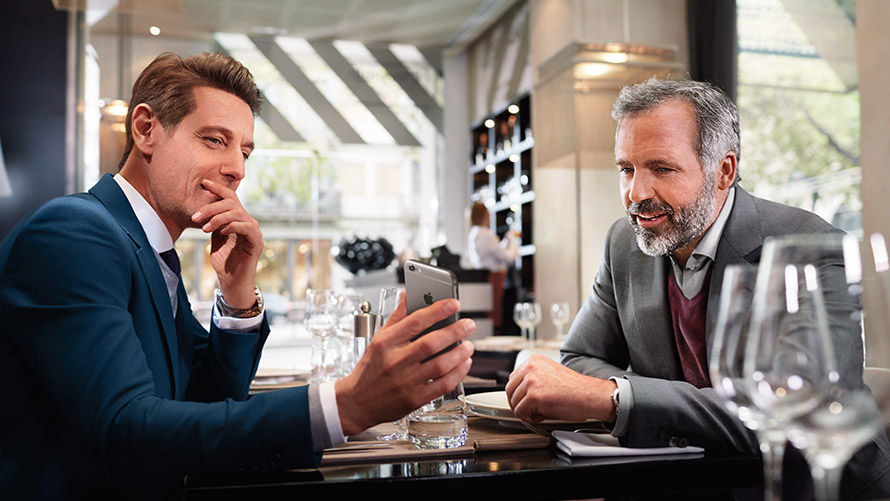 Manage your favourite Locations Two men in restaurant using feature „Manage your favorite Locations“ on smartphone