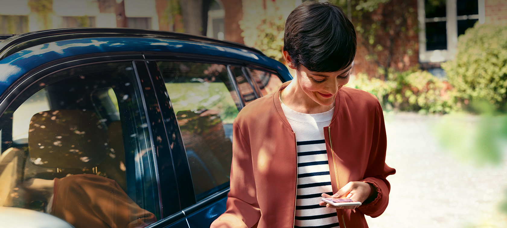 BMW Teleservices Woman looking at her smartphone BMW Teleservices Woman in front of BMW looking at her smartphone