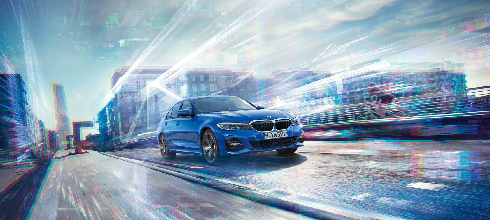 Front view of driving BMW 3 Series Sedan by day under glass building.