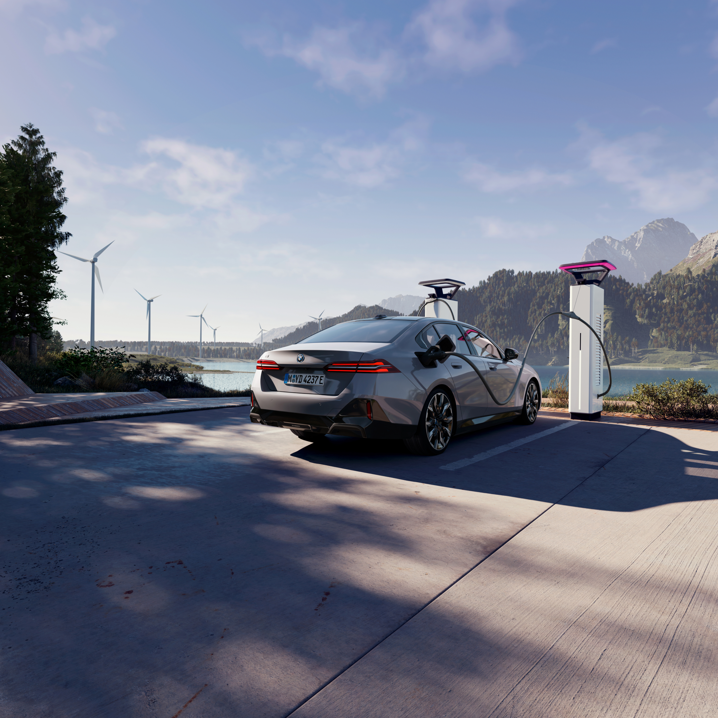 BMW charging at a charging post with views of water, mountains and wind turbines